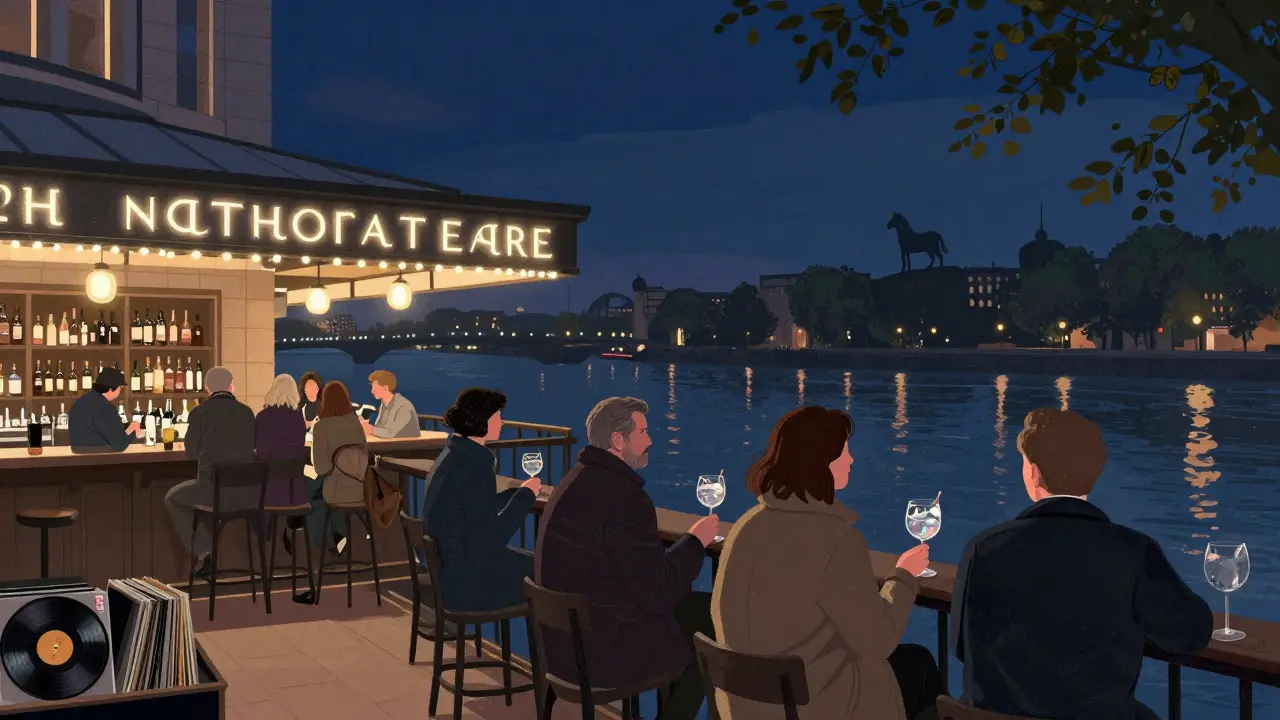 Patrons on a terrace overlooking the Thames after a National Theatre performance, drinks in hand.